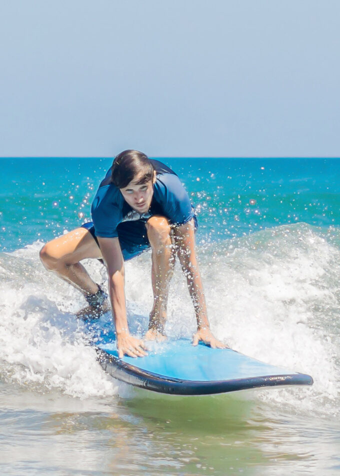Young man, beginner Surfer learns to surf on a sea foam on the Bali island. BANNER, long format